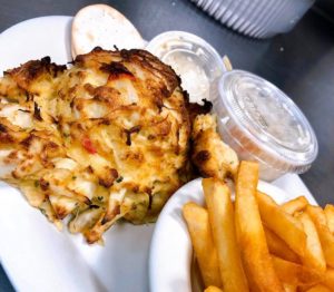 a shipment of crab cakes cooked and served with fries and sauce