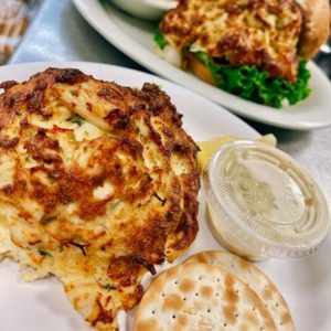 box hill crab cakes large crab cake on a plate with crackers